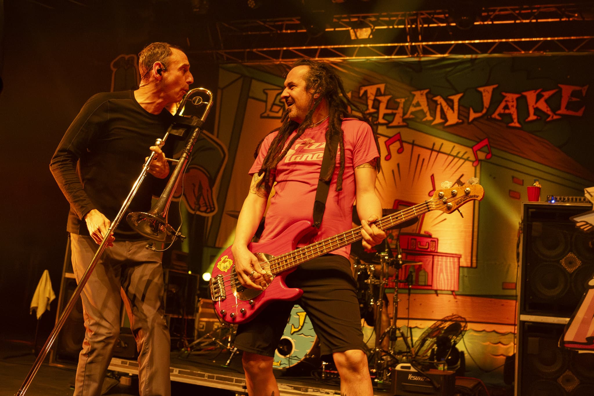 Less Than Jake performing live with trombone and bass under orange stage lights
